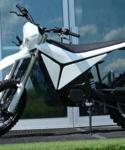White Volt Surge V electric dirt bike parked on a paved path in Australia, side view showing knobby off-road tyres and minimalist electric motor design