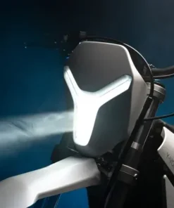 "Close-up of the Y-Volt Surge V electric dirt bike's Y-shaped LED headlight glowing white against a dark studio background, Australia