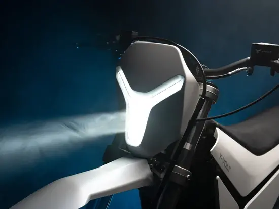 "Close-up of the Y-Volt Surge V electric dirt bike's Y-shaped LED headlight glowing white against a dark studio background, Australia